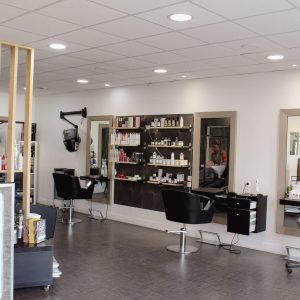 photo de salon de coiffure avec des fauteuils et des miroirs