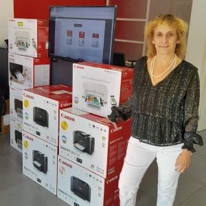 photo de carole de concept media services avec une pile de boite d'imprimante à côté