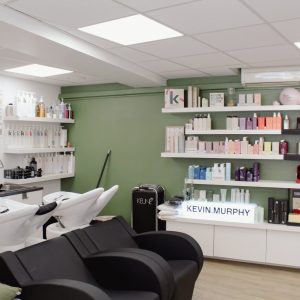 salon avec bacs de coiffure et étagères de produits cosmetiques de Bellezza Di à Bollène
