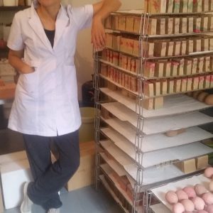 Photo d'une femme à coté d'un portant contenant les produits cosmetiques de Serto Cosmetiques Bollène
